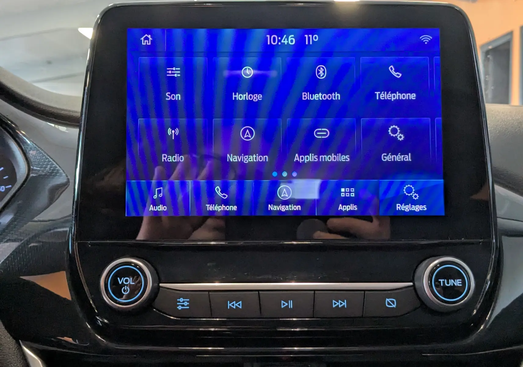 Écran tactile central du tableau de bord du Ford Puma 2020 avec interface bleue et commandes audio intégrées.