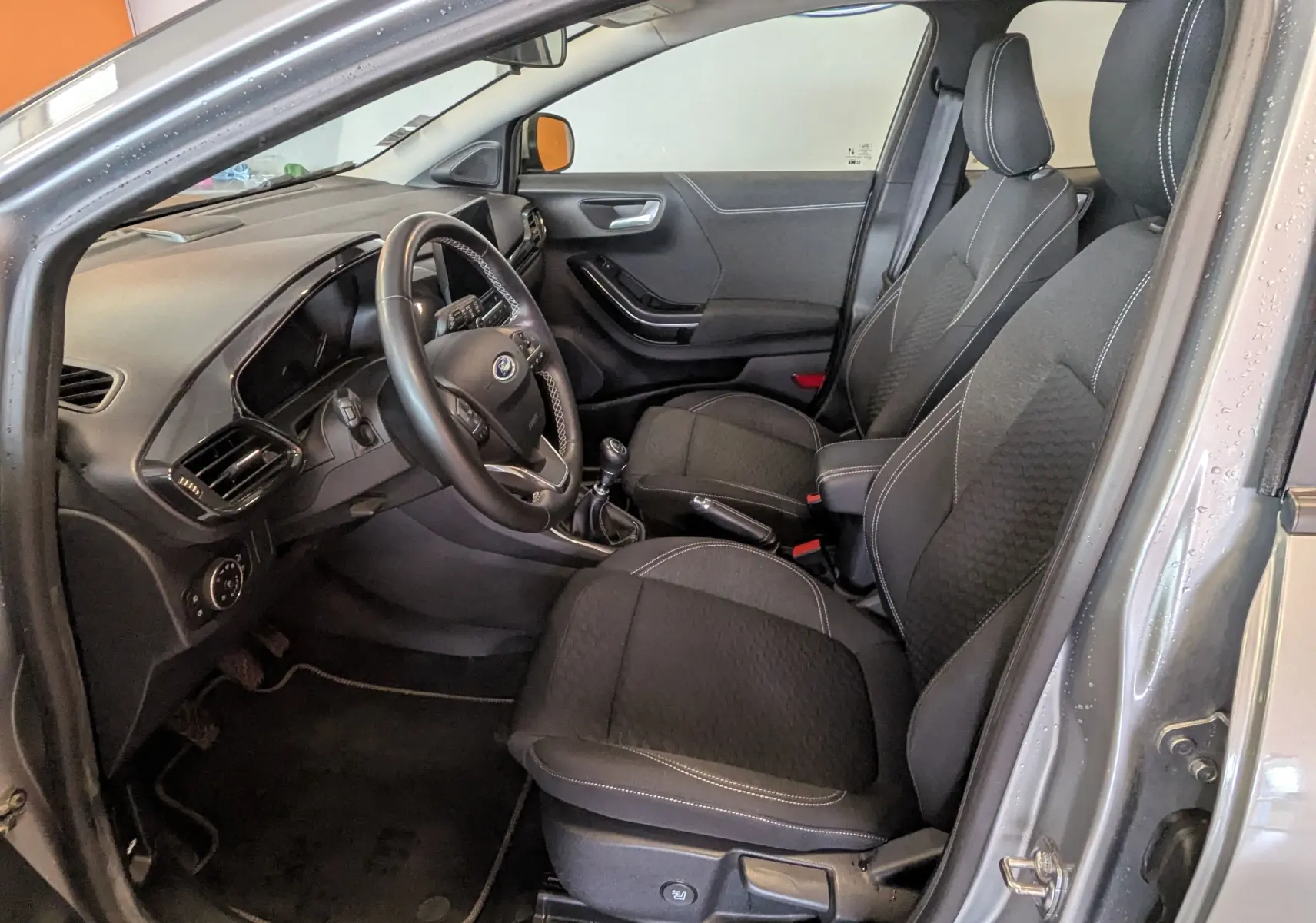 Vue intérieure côté conducteur du Ford Puma gris 2020, montrant sièges noirs et tableau de bord avec volant multifonction.