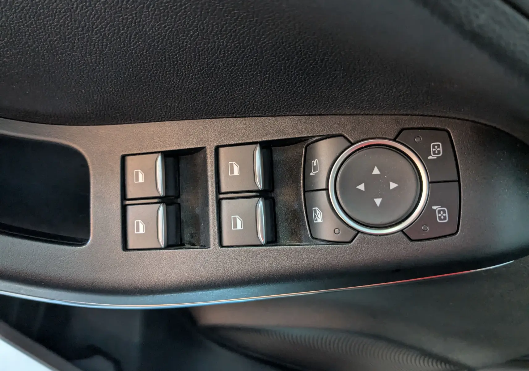 Gros plan sur les commandes de lève-vitres et réglage des rétroviseurs côté conducteur du Ford Puma gris 2020.