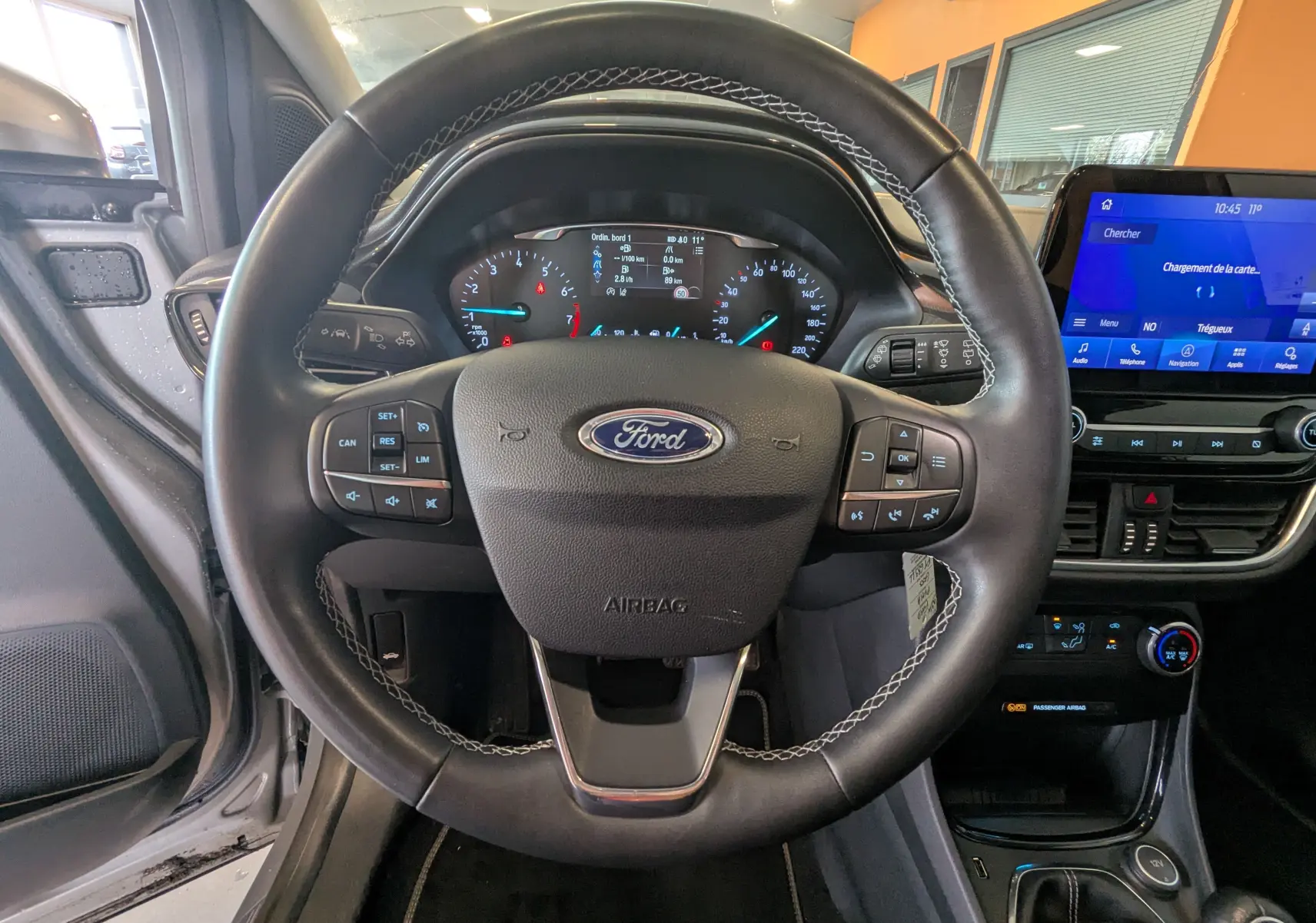 Vue centrée sur le volant noir du Ford Puma 2020 avec tableau de bord et écran tactile bleu en arrière-plan.