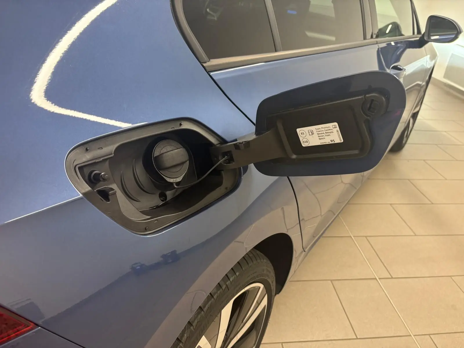 Vue arrière côté gauche d'une Volkswagen Golf Bleu Anémone avec trappe à carburant ouverte et jante alliage 18 pouces.
