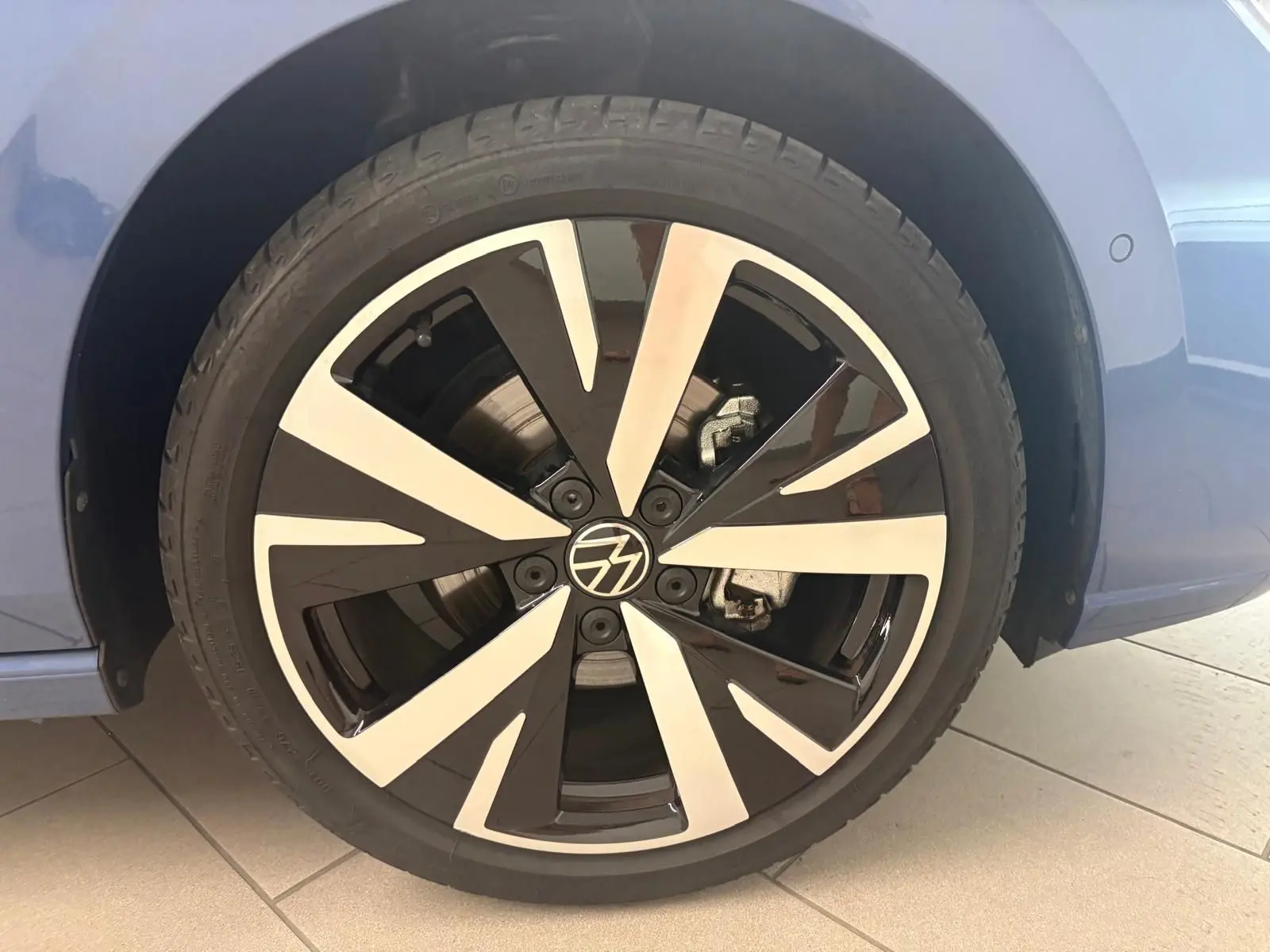 Gros plan sur la jante alliage 18'' Catania bicolore noir et argent d'une Volkswagen Golf Bleu Anémone côté arrière droit.
