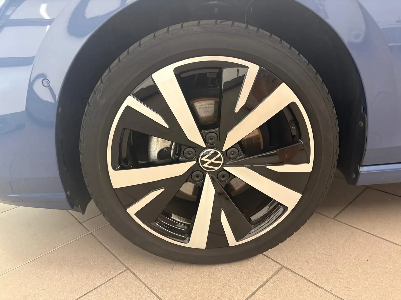 Gros plan sur la jante alliage 18'' Catania bicolore noir et argent d'une Volkswagen Golf Bleu Anémone.