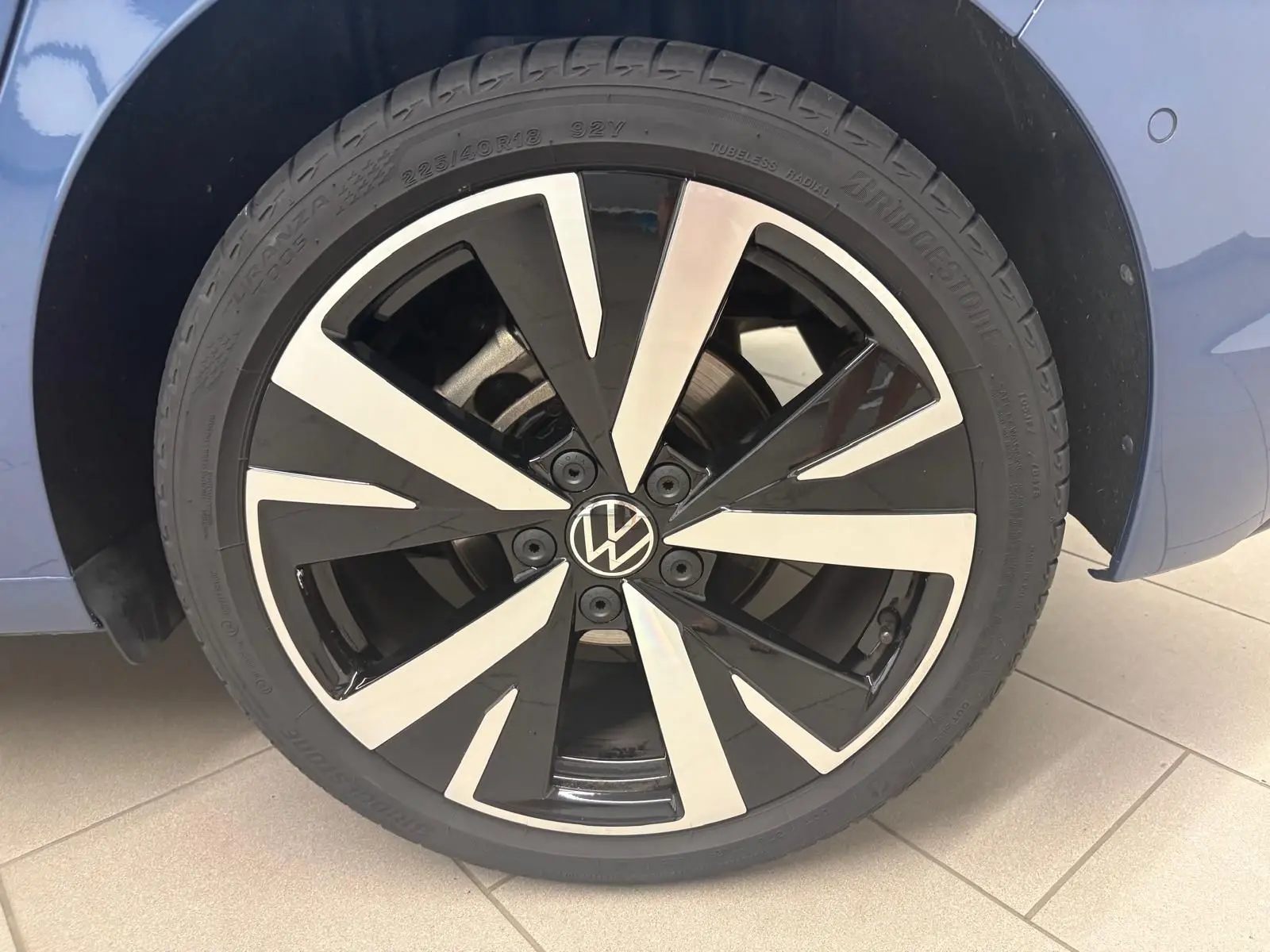 Gros plan sur la jante alliage 18'' Catania bicolore noir et argent de la Volkswagen Golf Bleu Anémone, côté gauche.