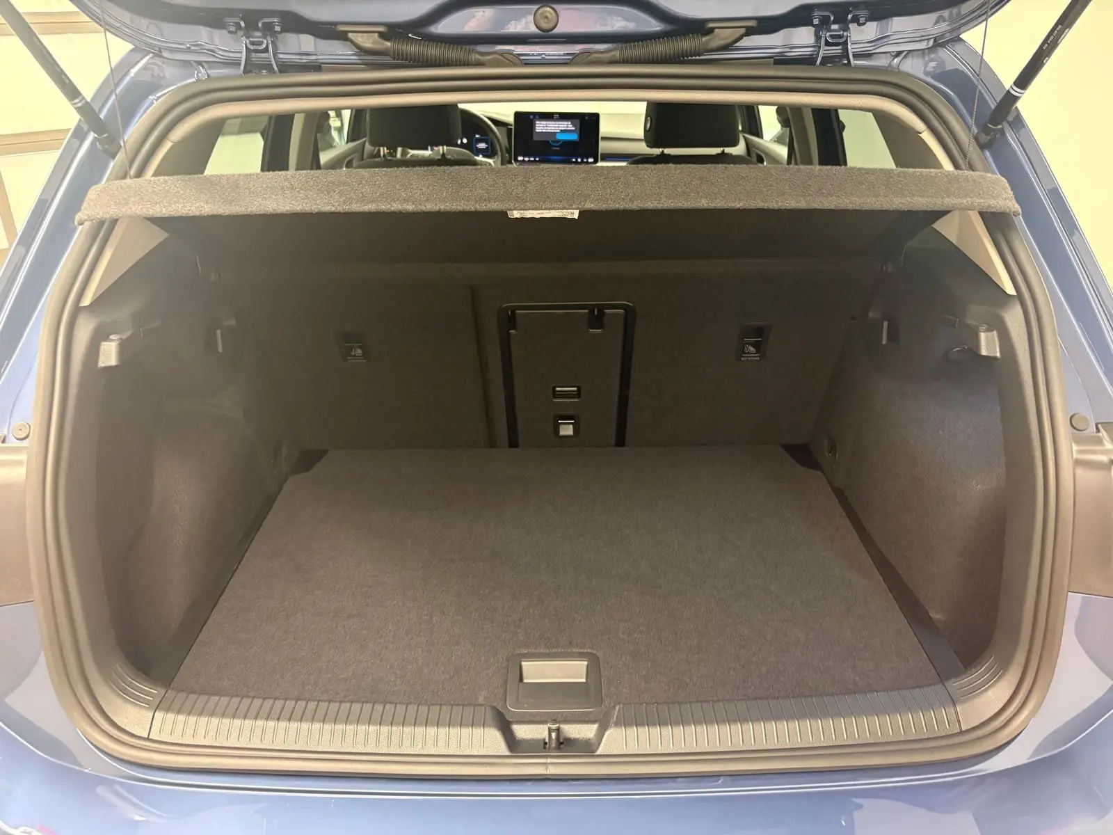 Coffre ouvert vu de l'arrière d'une Volkswagen Golf Bleu Anémone, montrant l'espace de chargement et la tablette arrière.