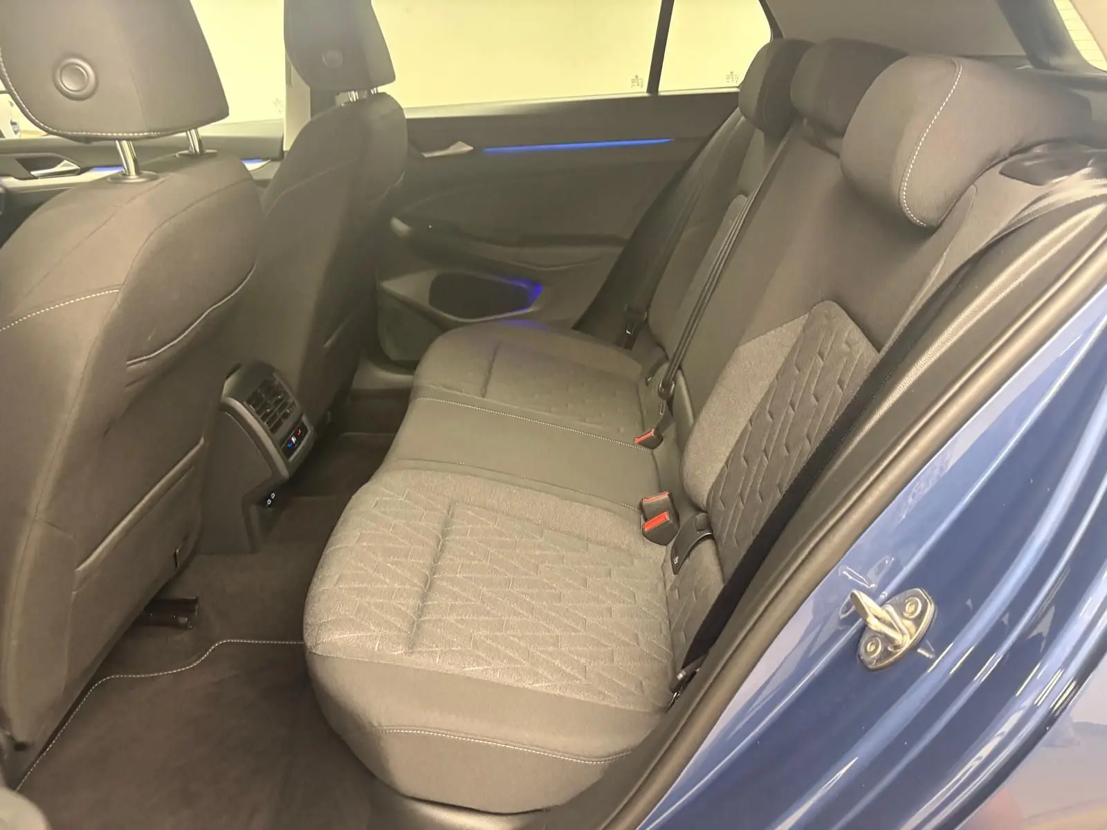 Vue intérieure côté droit des sièges arrière gris et de la portière bleu anémone d'une Volkswagen Golf 1.5 TSI 2025.