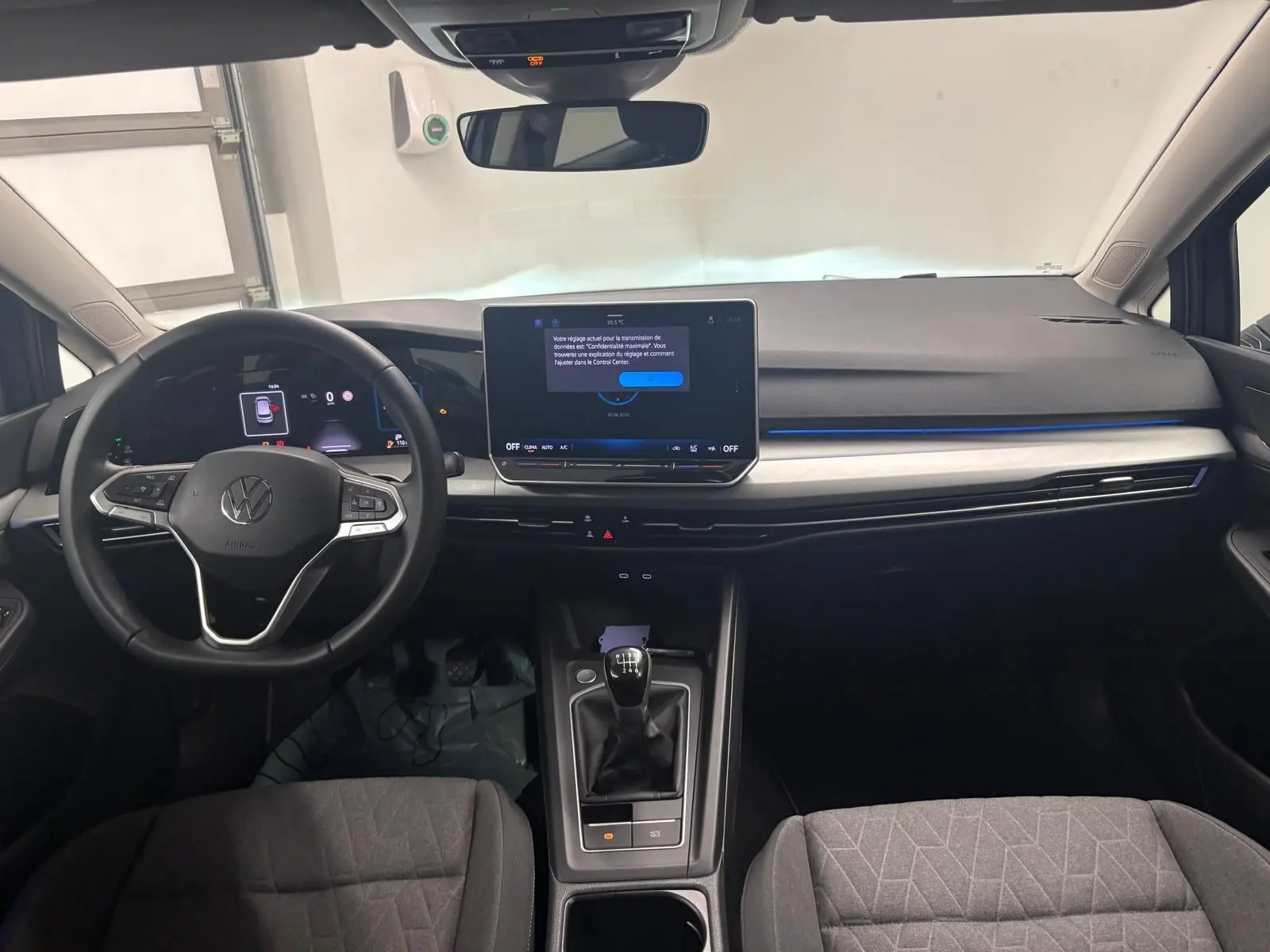 Vue intérieure avant du tableau de bord de la Volkswagen Golf Bleu Anémone avec écran tactile et volant multifonction.
