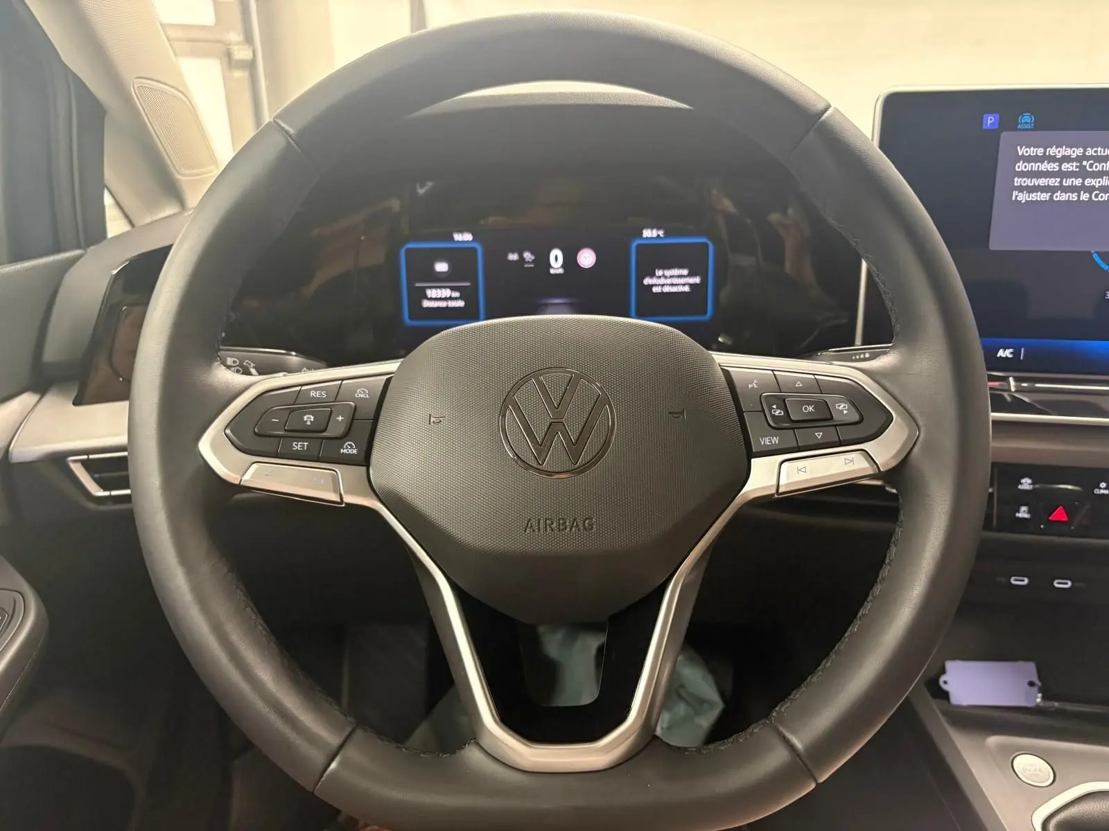 Vue rapprochée du volant noir de la Volkswagen Golf 1.5 TSI 2025 avec commandes intégrées et tableau de bord numérique.