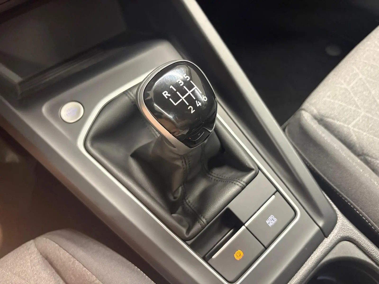 Gros plan sur le levier de vitesse manuel noir et cuir de la Volkswagen Golf, entouré de la console centrale grise.