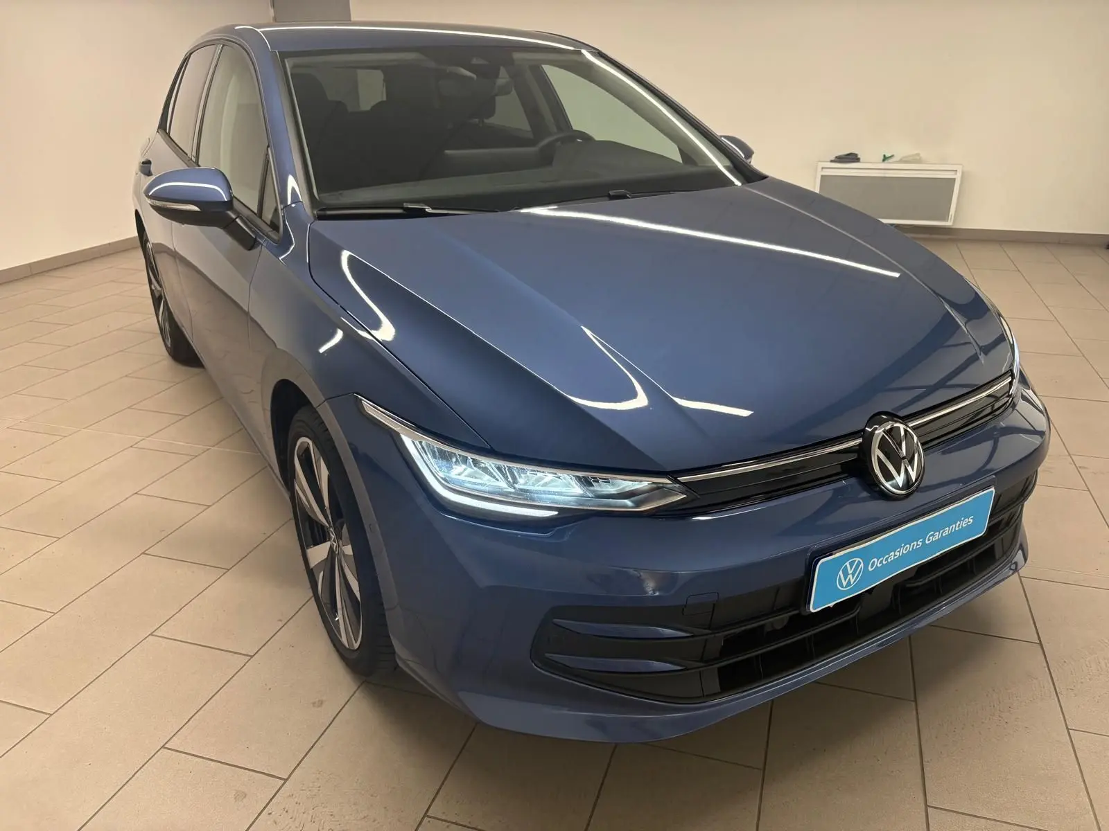 Volkswagen Golf 1.5 TSI Bleu Anémone vue 3/4 avant avec jantes alliage 18'' Catania en intérieur showroom.