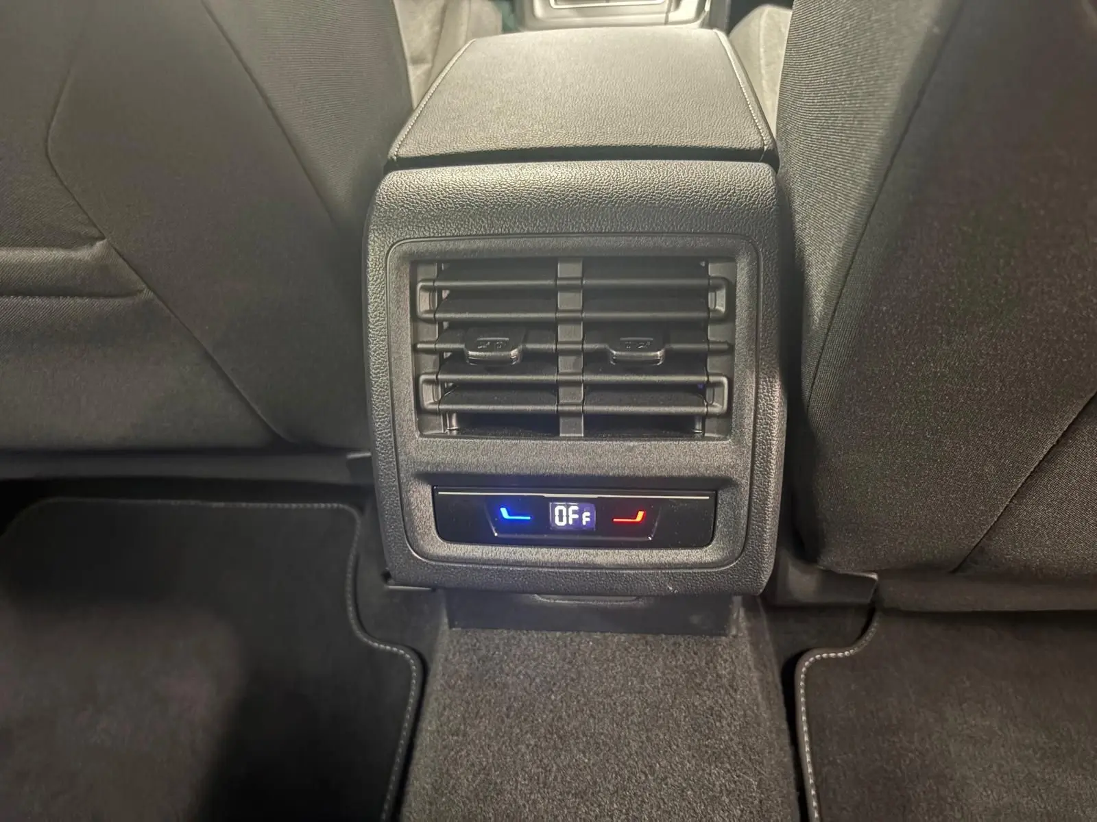 Détail de la console arrière avec diffuseurs d'air et commandes de climatisation, intérieur tissu noir.