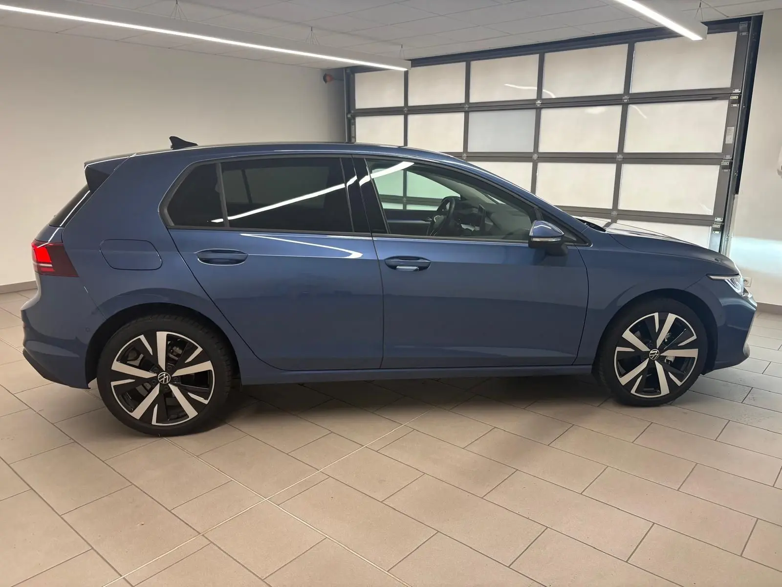 Profil droit d'une Volkswagen Golf 1.5 TSI 2025 en bleu Anémone avec jantes alliage léger 18'' Catania.