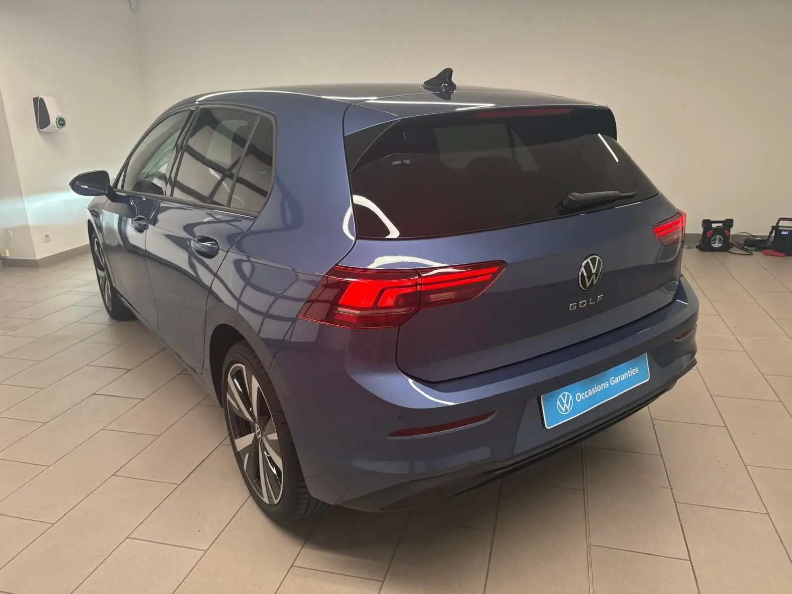 Vue 3/4 arrière droite d'une Volkswagen Golf 1.5 TSI 2025 en bleu anémone avec jantes alliage 18'' Catania.