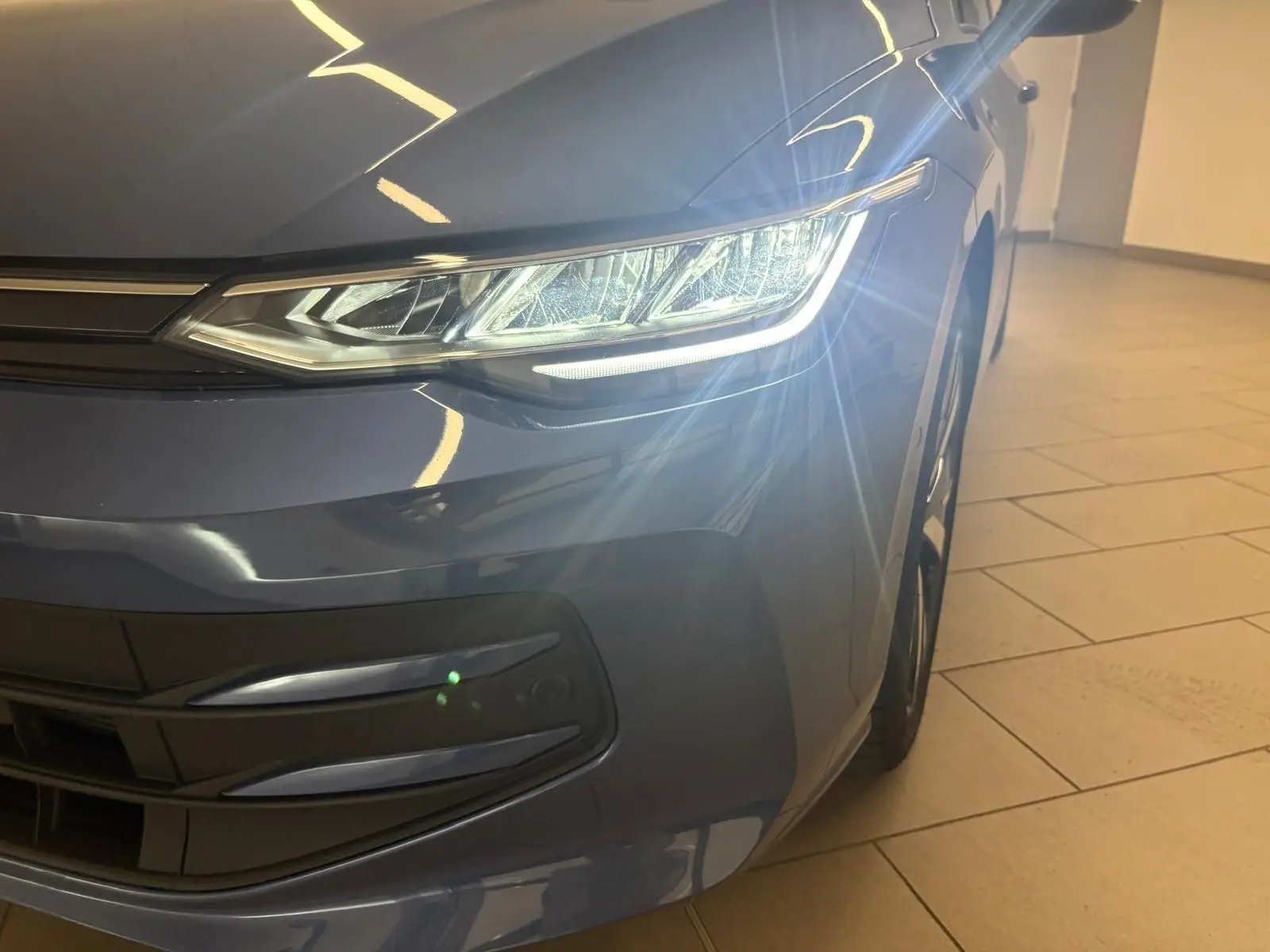 Gros plan sur l'avant droit de la Volkswagen Golf Bleu Anémone avec phare allumé et jante alliage 18 pouces.