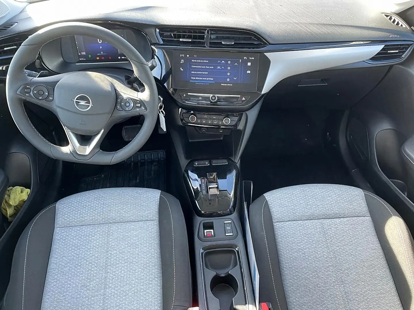 Vue intérieure avant de l’Opel Corsa 1.2 turbo 2025 avec tableau de bord noir, écran tactile et sièges tissu gris clair.