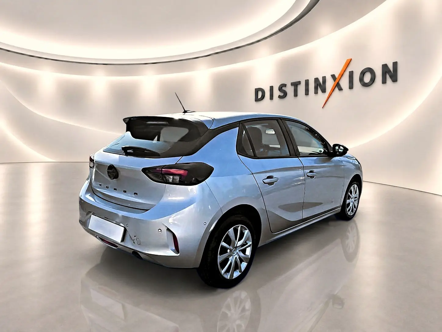 Opel Corsa gris alu vue 3/4 arrière droit en intérieur avec toit noir et becquet arrière distinctif.