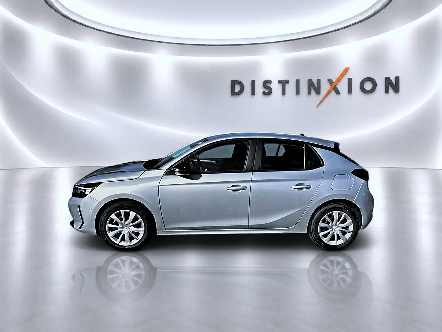 Profil droit d'une Opel Corsa gris alu 2025 avec jantes alliage, sur fond blanc lumineux avec logo Distinxion.