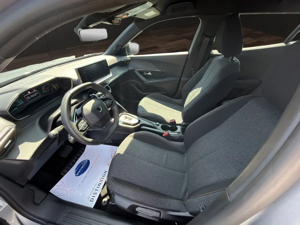Vue intérieure côté conducteur du Peugeot 2008 Hybrid 145 e-DCS6 STYLE 2025 avec sièges gris et tableau de bord moderne.