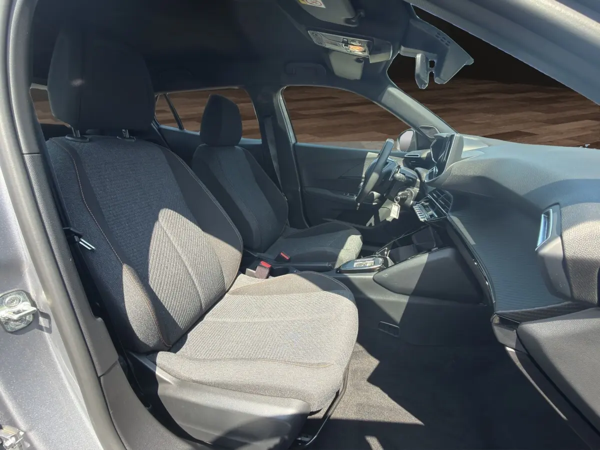 Vue intérieure côté conducteur du Peugeot 2008 Hybrid 145 gris clair, montrant sièges tissu et tableau de bord moderne.