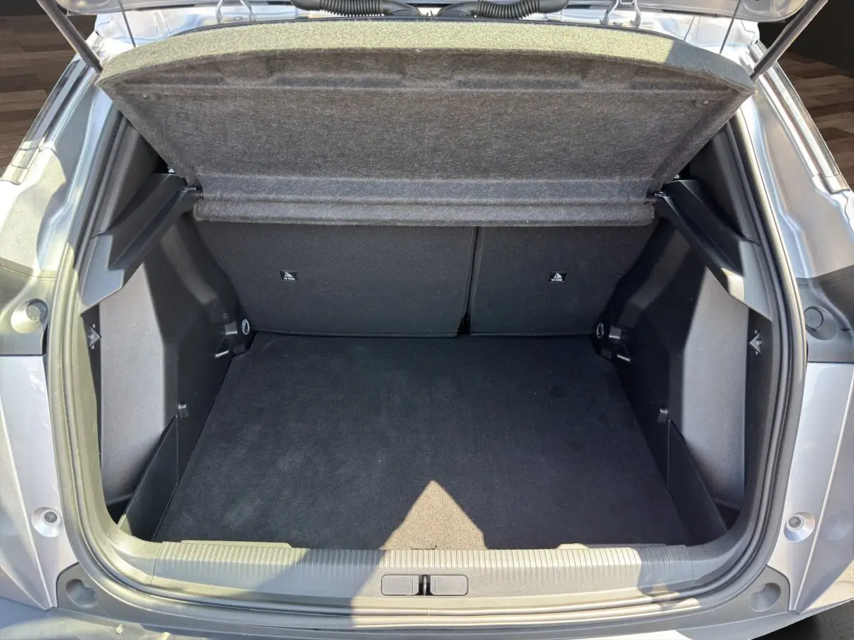 Coffre ouvert vu de l'arrière d'un Peugeot 2008 Hybrid 145 gris clair, espace de chargement propre et vide.