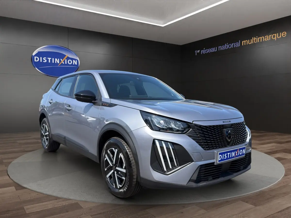 Peugeot 2008 Hybrid 145 e-DCS6 STYLE gris clair en 3/4 avant droit, avec calandre noire et feux LED distinctifs.