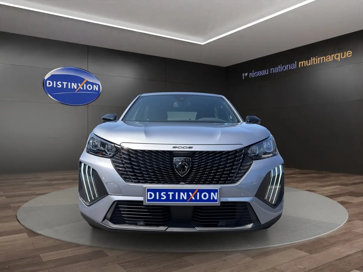 Vue frontale d'un Peugeot 2008 Hybrid 145 gris clair avec calandre noire et feux LED verticaux distinctifs.