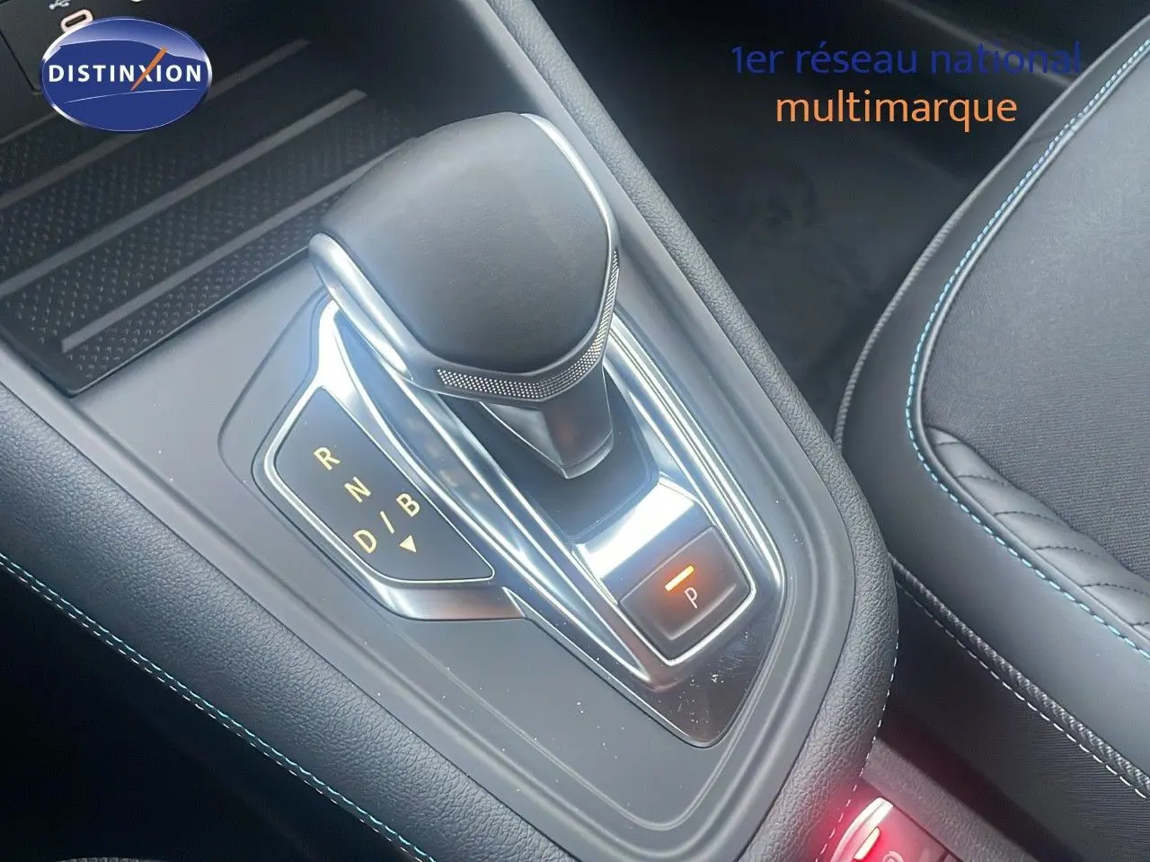 Le levier de vitesse automatique noir et chrome du Renault Captur E-Tech hybride, avec surpiqûres bleues visibles sur l'assise.