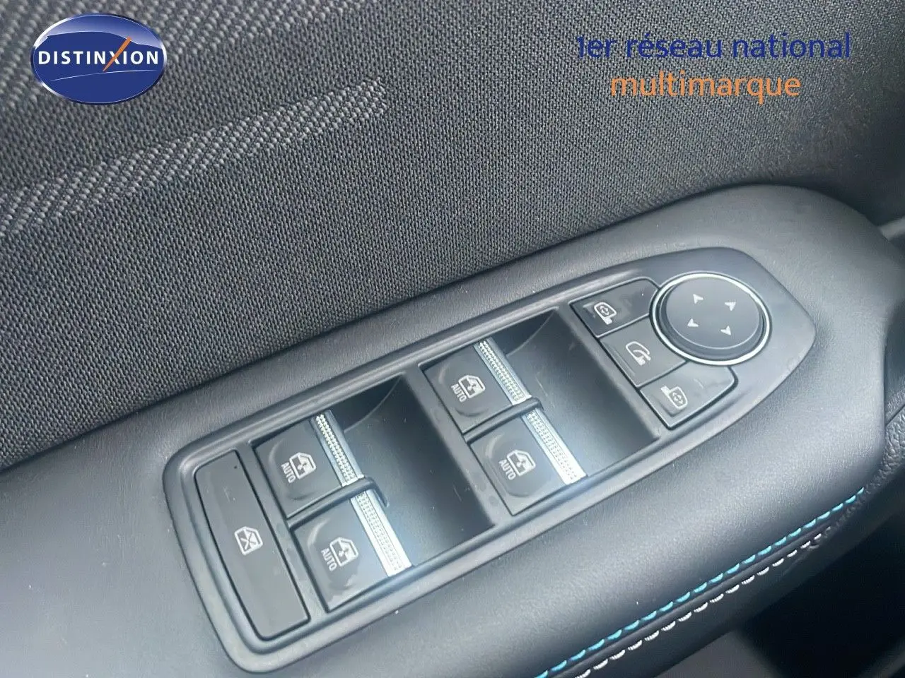 Gros plan sur les commandes des vitres électriques et rétroviseurs côté conducteur du Renault Captur rouge passion toit noir.