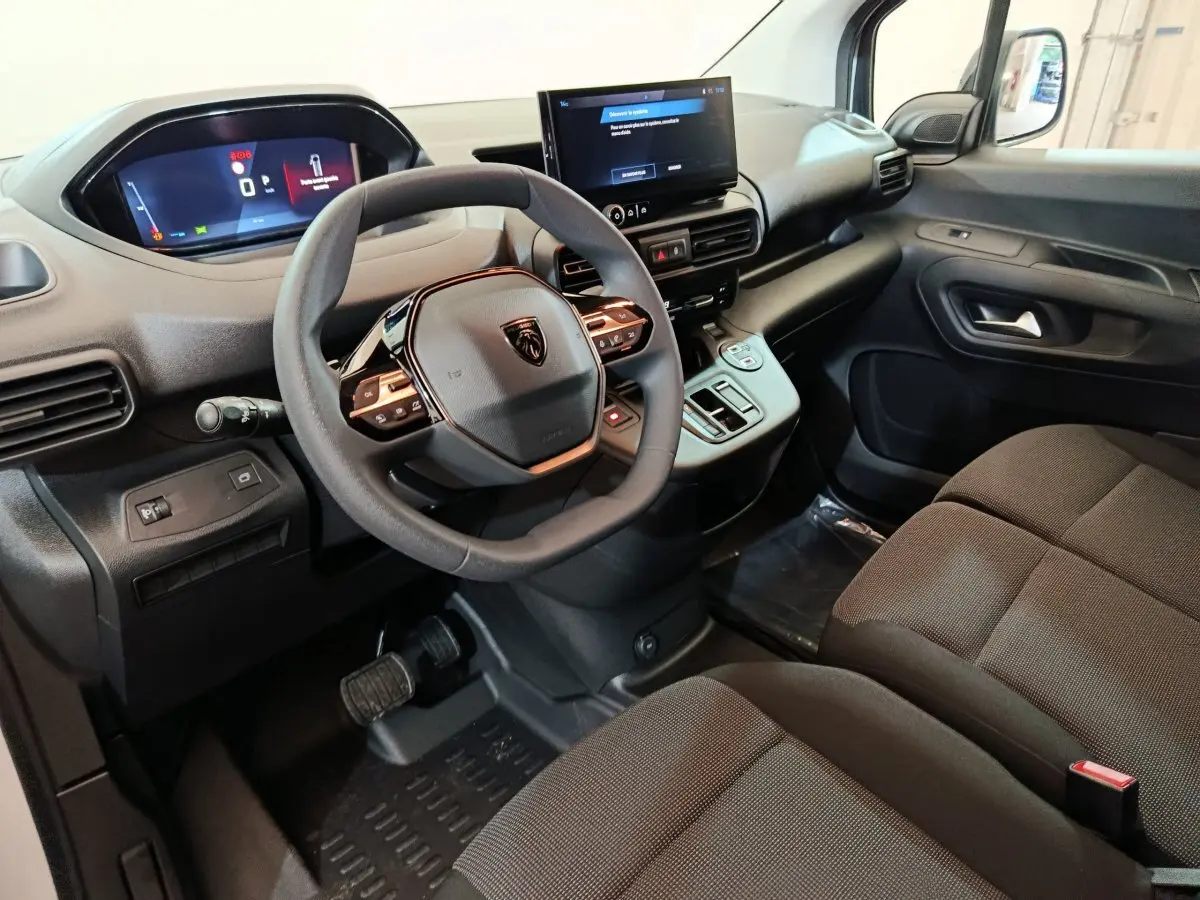 Intérieur du Peugeot Partner XL 2025 vu côté conducteur, tableau de bord moderne avec écran tactile et volant multifonction noir.