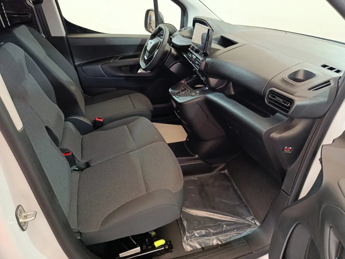 Intérieur avant du Peugeot Partner XL 2025 blanc, montrant sièges gris et tableau de bord moderne avec écran tactile central.