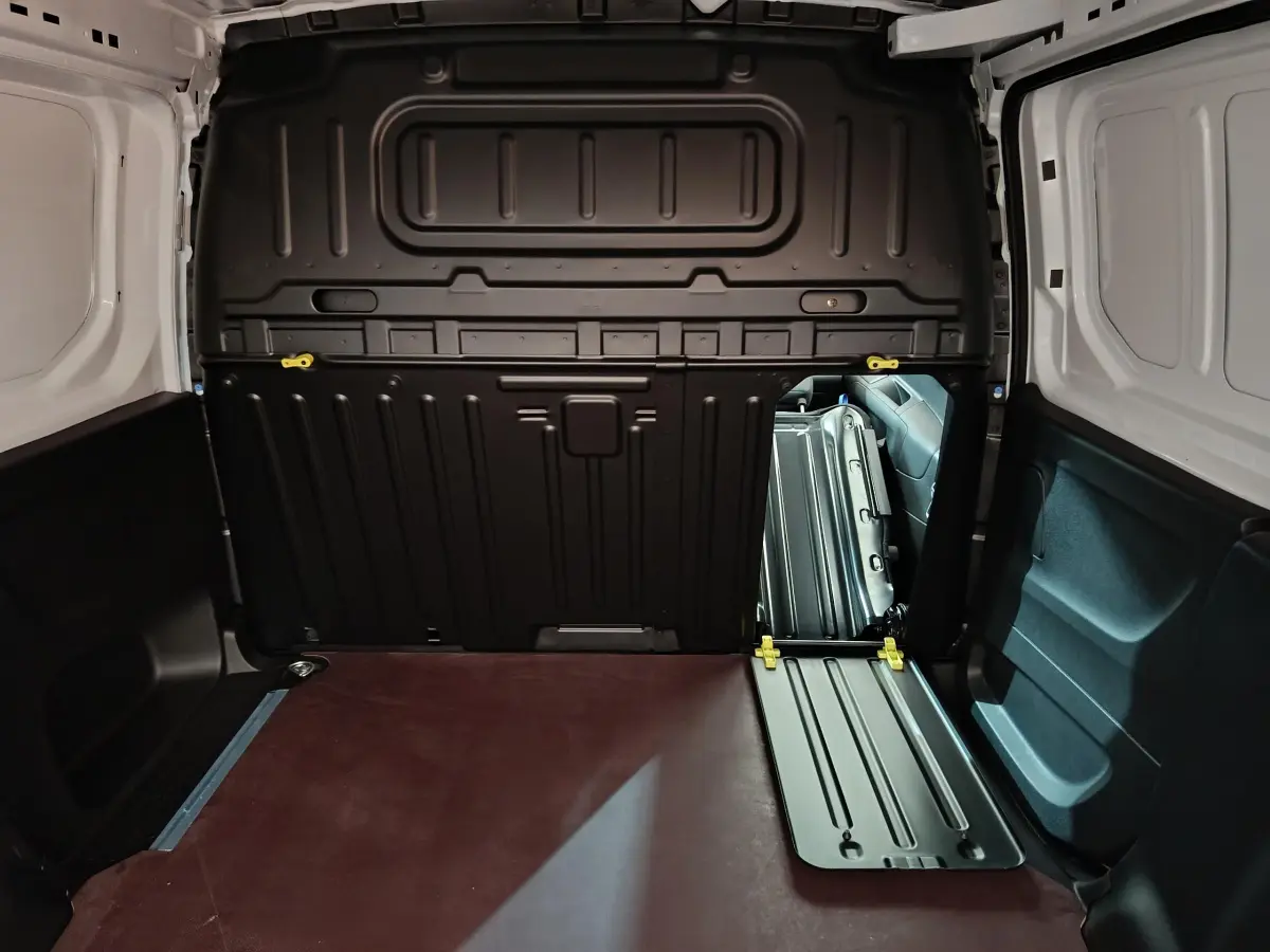 Vue intérieure du coffre blanc du Peugeot Partner XL 950kg avec cloison pleine noire et plancher marron.