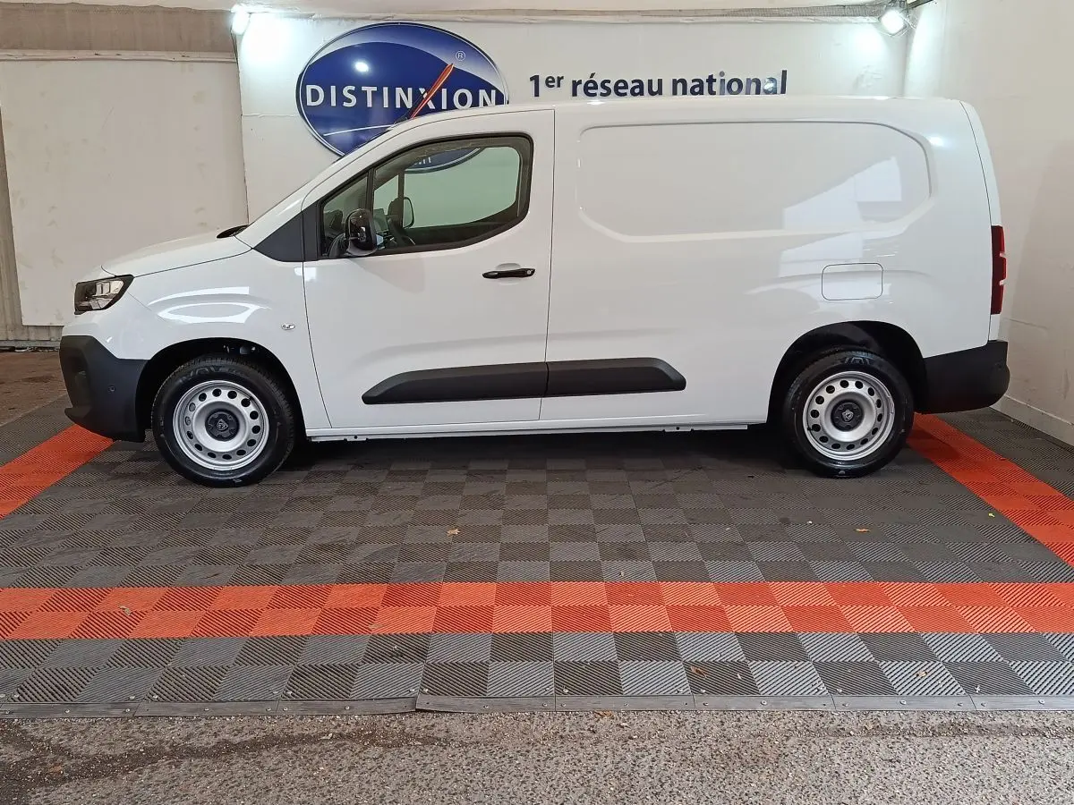 Vue de profil côté gauche d'un utilitaire blanc Peugeot Partner XL 950kg Diesel 2025 avec jantes acier et protections noires.