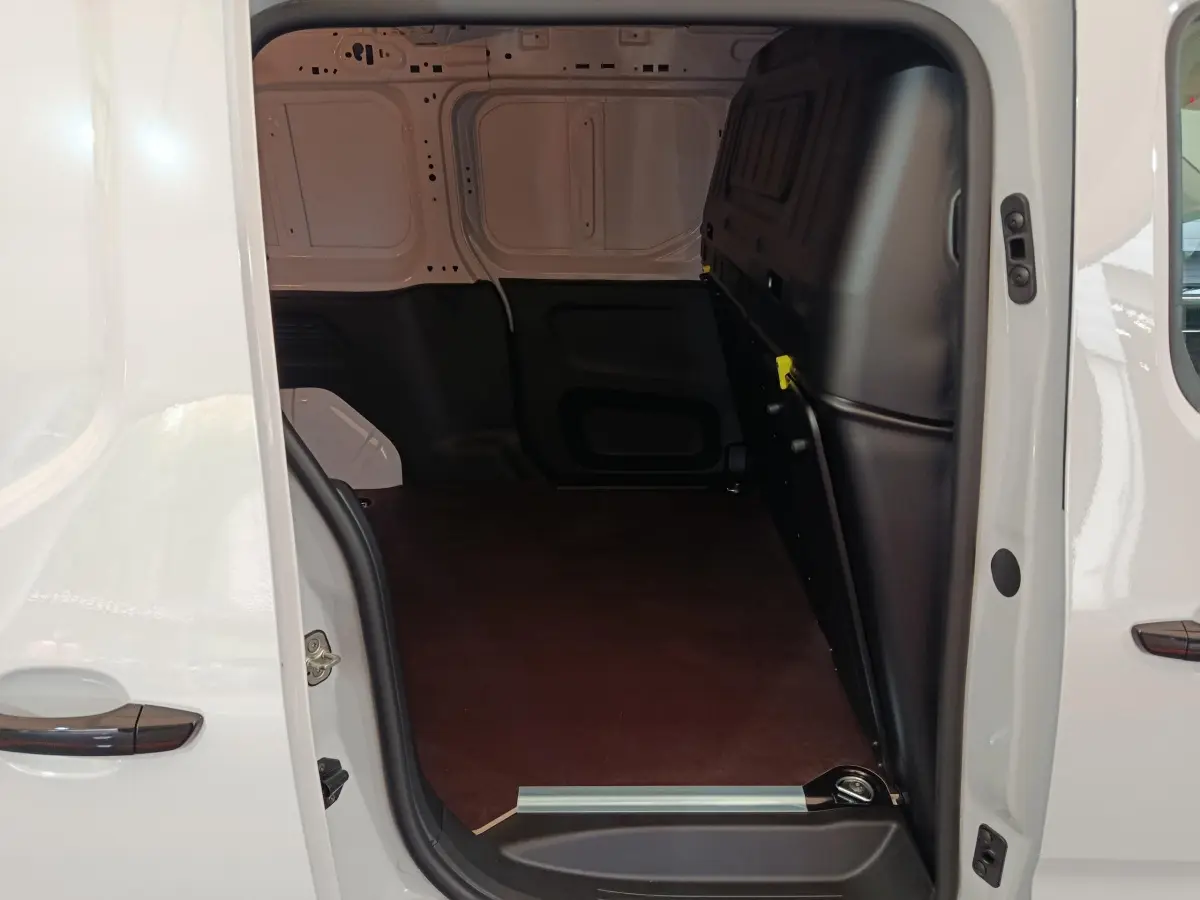Vue intérieure du coffre côté droit d'un Peugeot Partner XL blanc, montrant l'espace de chargement vide et la cloison pleine noire.