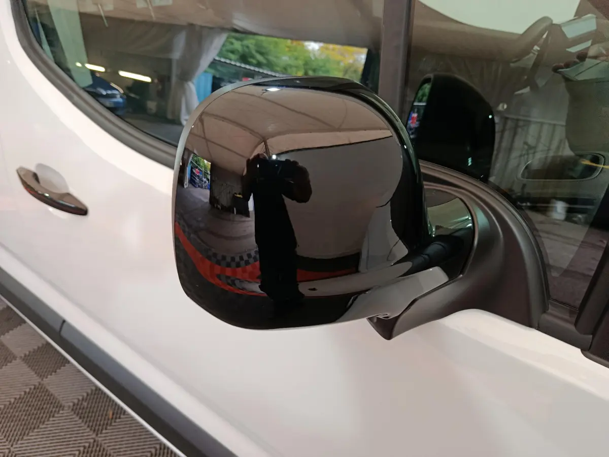 Rétroviseur noir côté conducteur du Peugeot Partner XL blanc 2025, vue rapprochée sur la portière avant.