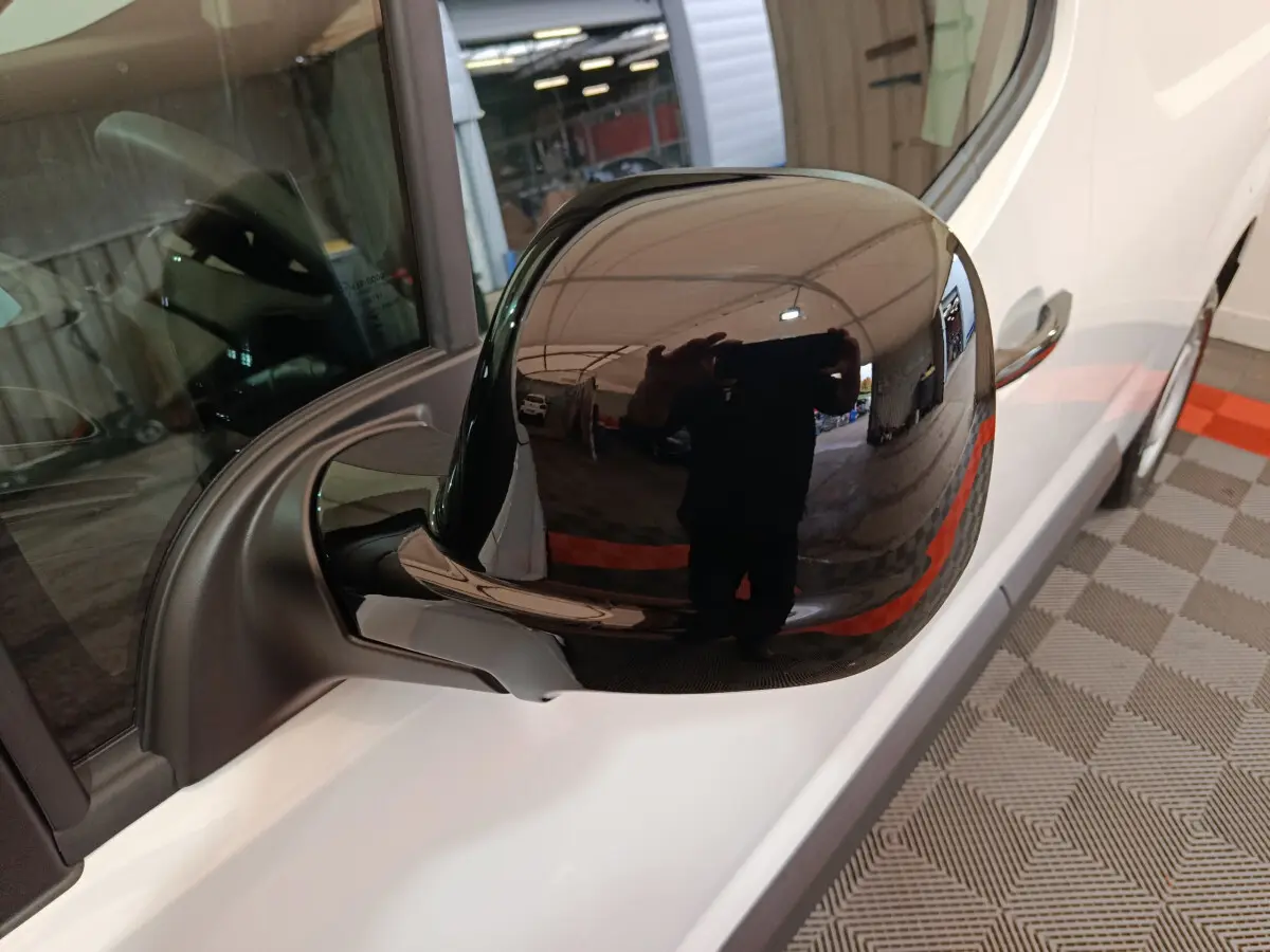 Rétroviseur noir côté conducteur du Peugeot Partner XL blanc, vue rapprochée en intérieur d'atelier.