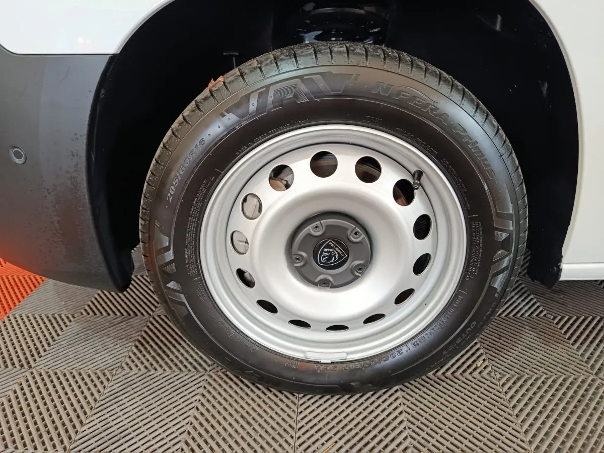 Gros plan sur la roue avant droite en jante acier argentée du Peugeot Partner blanc 2025.