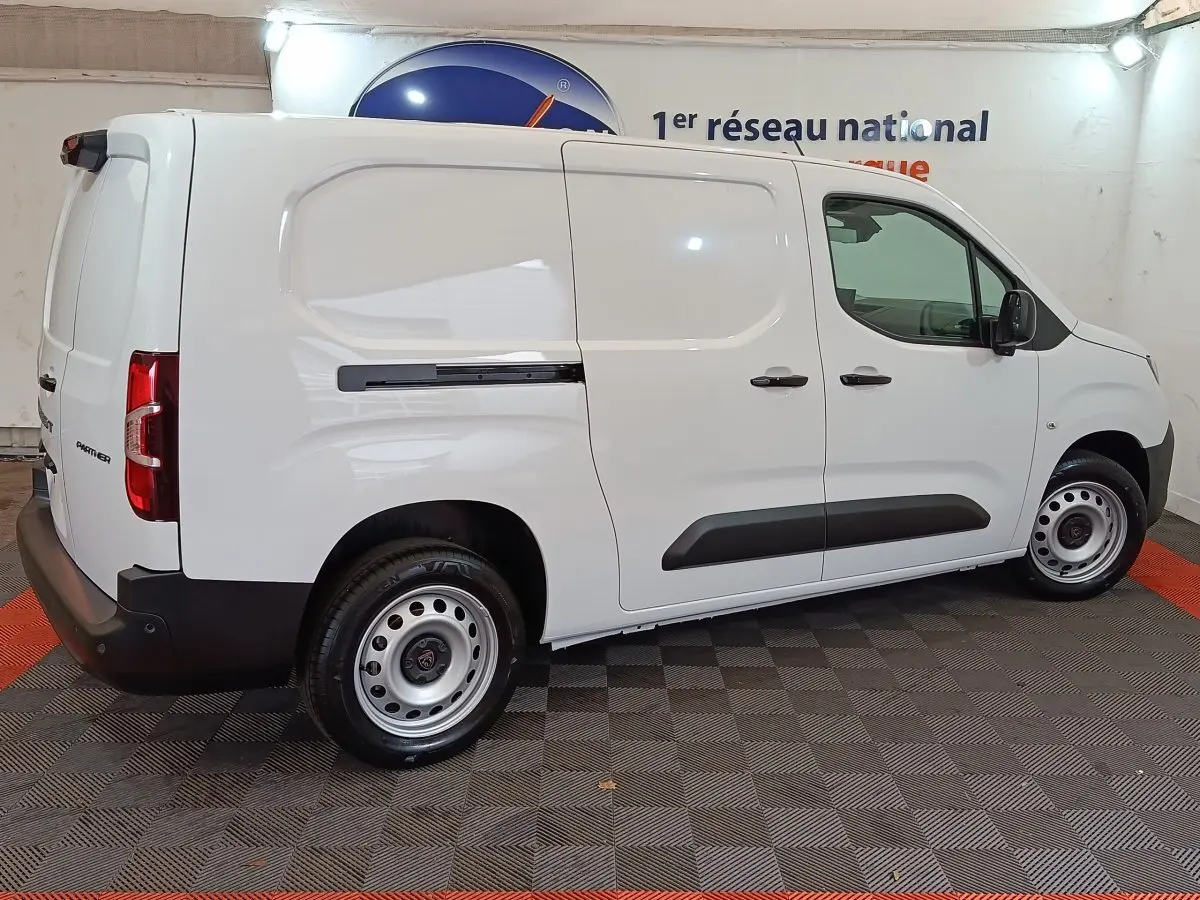Peugeot Partner XL blanc vu de profil côté droit dans un showroom avec jantes acier et protections noires.