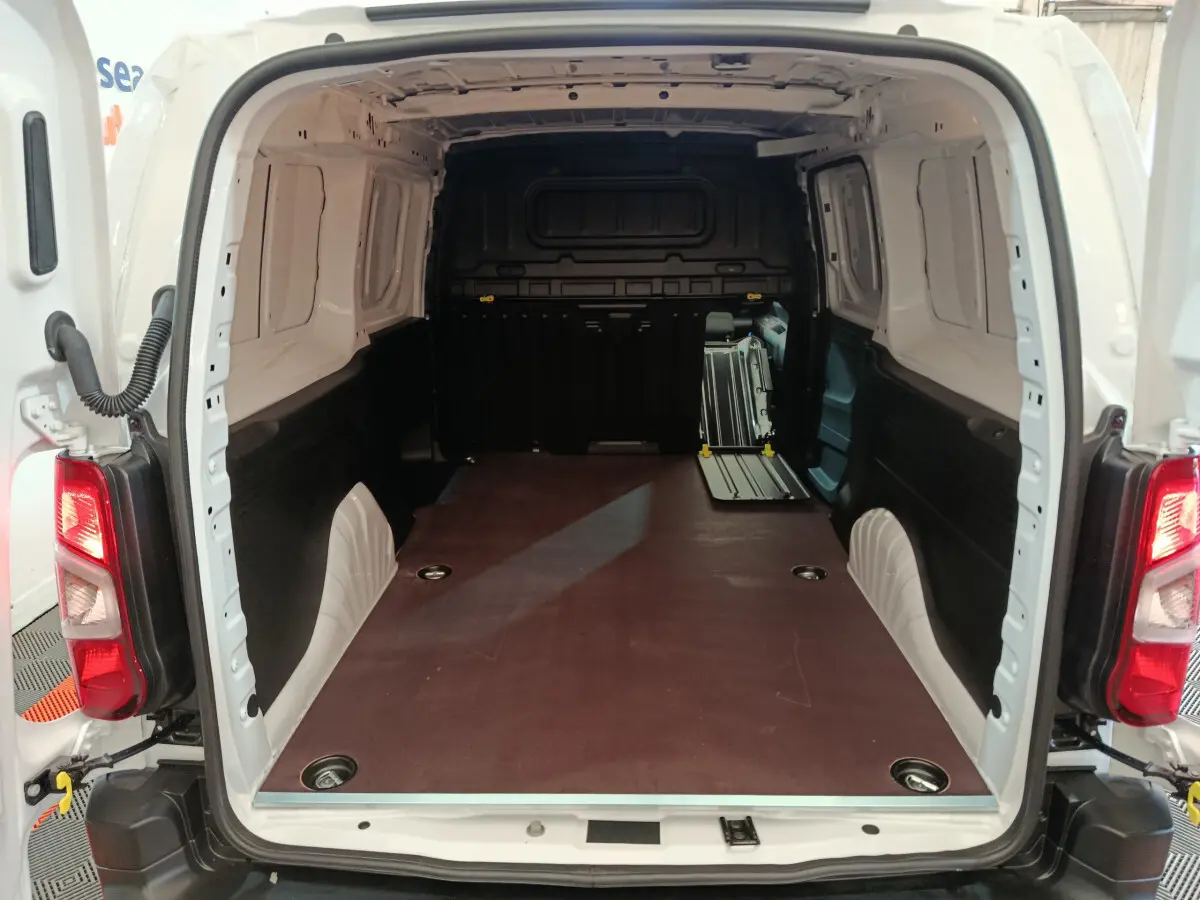 Vue arrière ouverte du Peugeot Partner XL blanc montrant l'espace de chargement vide avec plancher plat et cloison pleine noire.