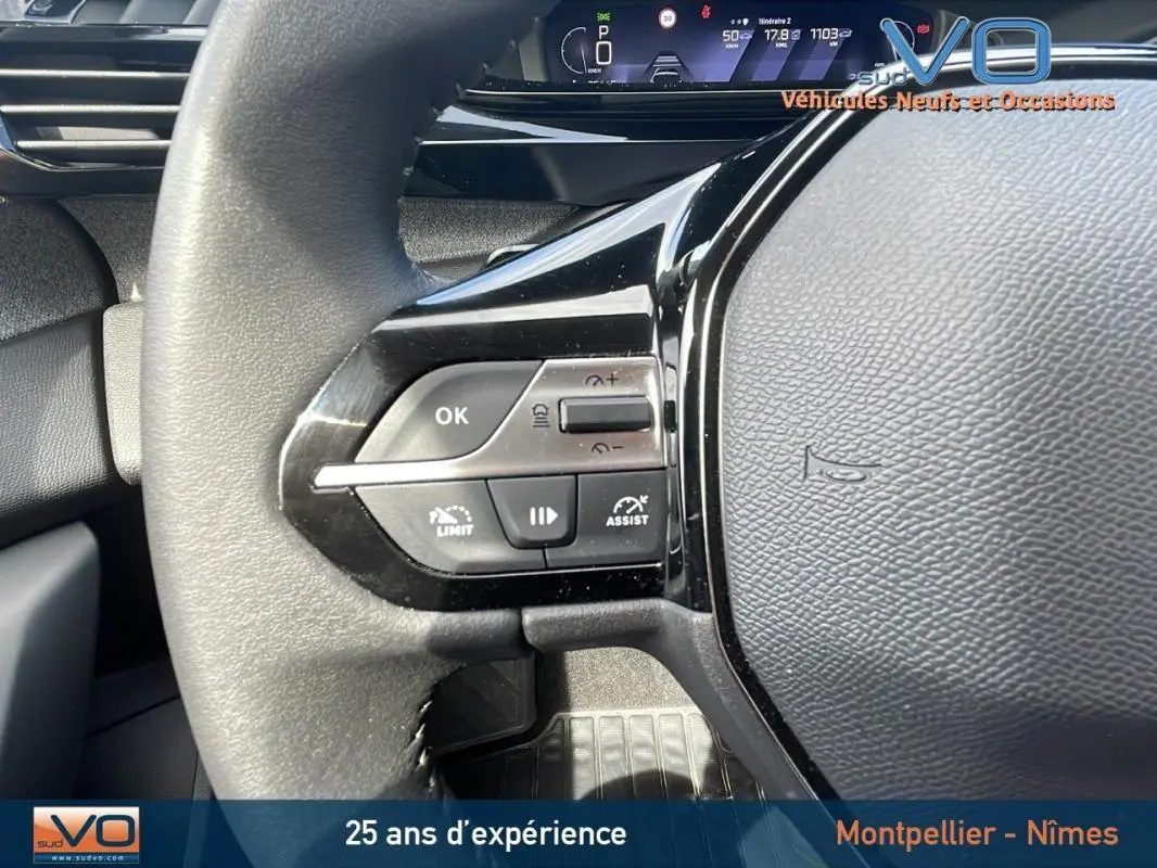 Gros plan sur le volant noir de la Peugeot 308 gris 2024, montrant les commandes de régulateur et limiteur de vitesse.