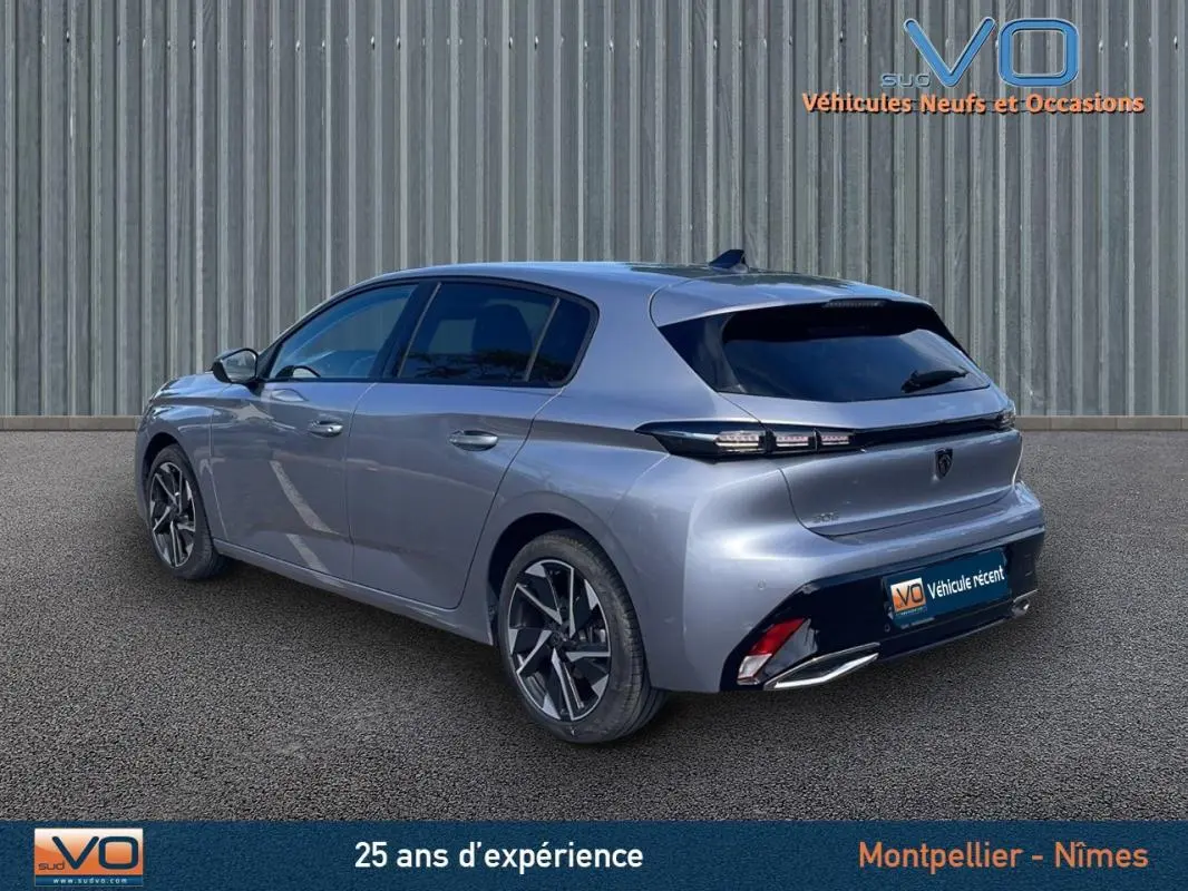 Vue 3/4 arrière droite d'une Peugeot 308 gris métallisé 2024, avec feux arrière LED et jantes alliage distinctives.