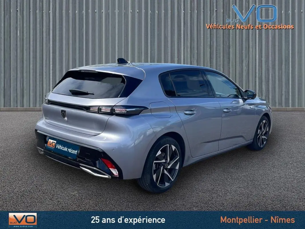 Peugeot 308 gris métallisé vue 3/4 arrière droit, avec jantes alliage et feux arrière LED distinctifs.