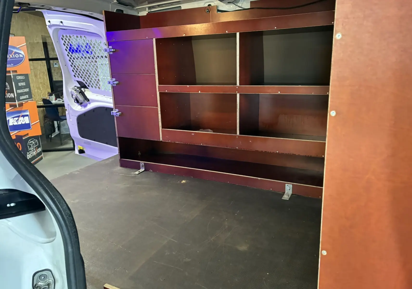 Vue intérieure arrière gauche du Citroën Berlingo blanc 2016 avec aménagements en bois pour rangement.