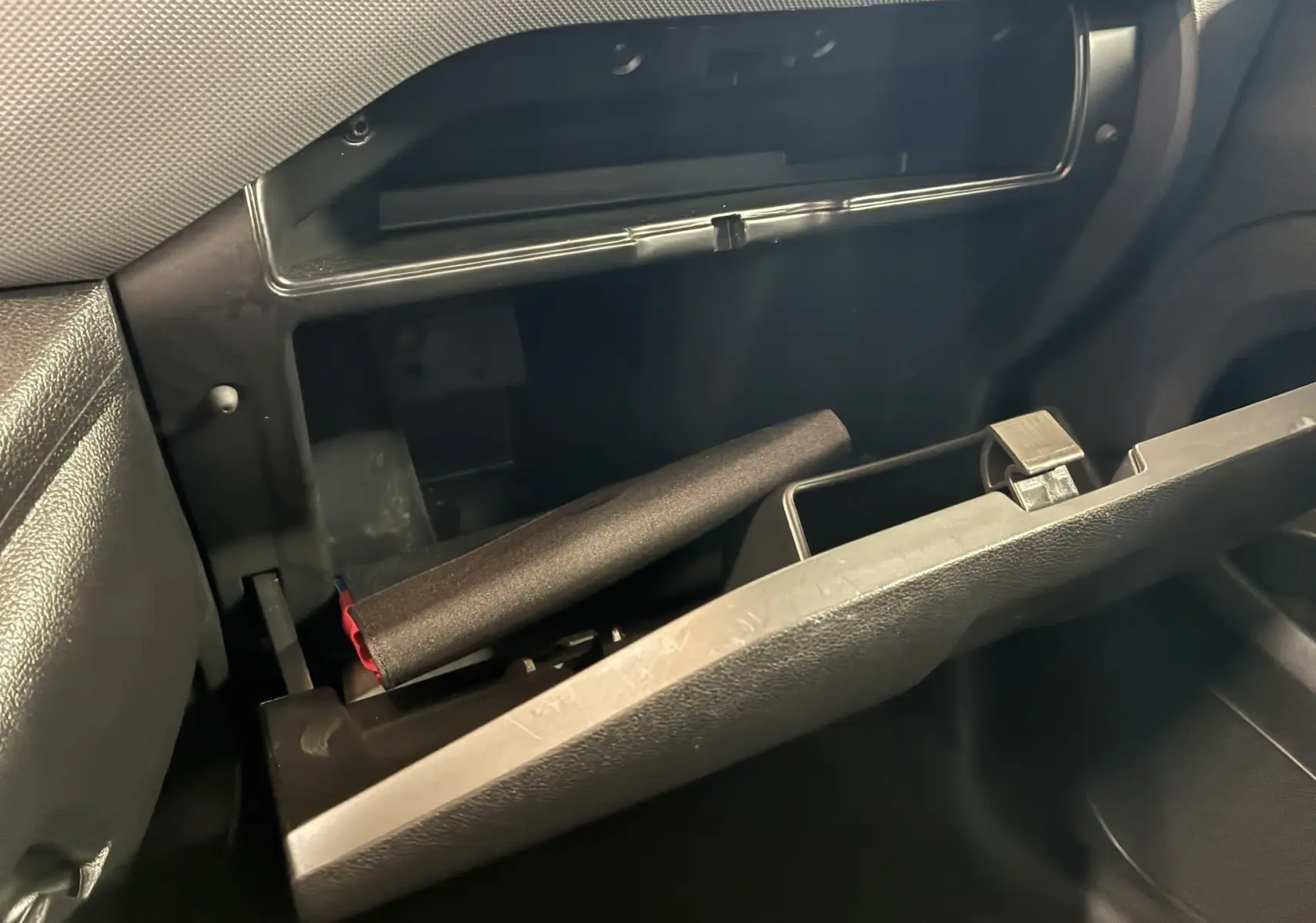 Vue intérieure du vide-poche côté passager ouvert du Citroën Berlingo blanc 2016, montrant un objet cylindrique noir à l'intérieur.
