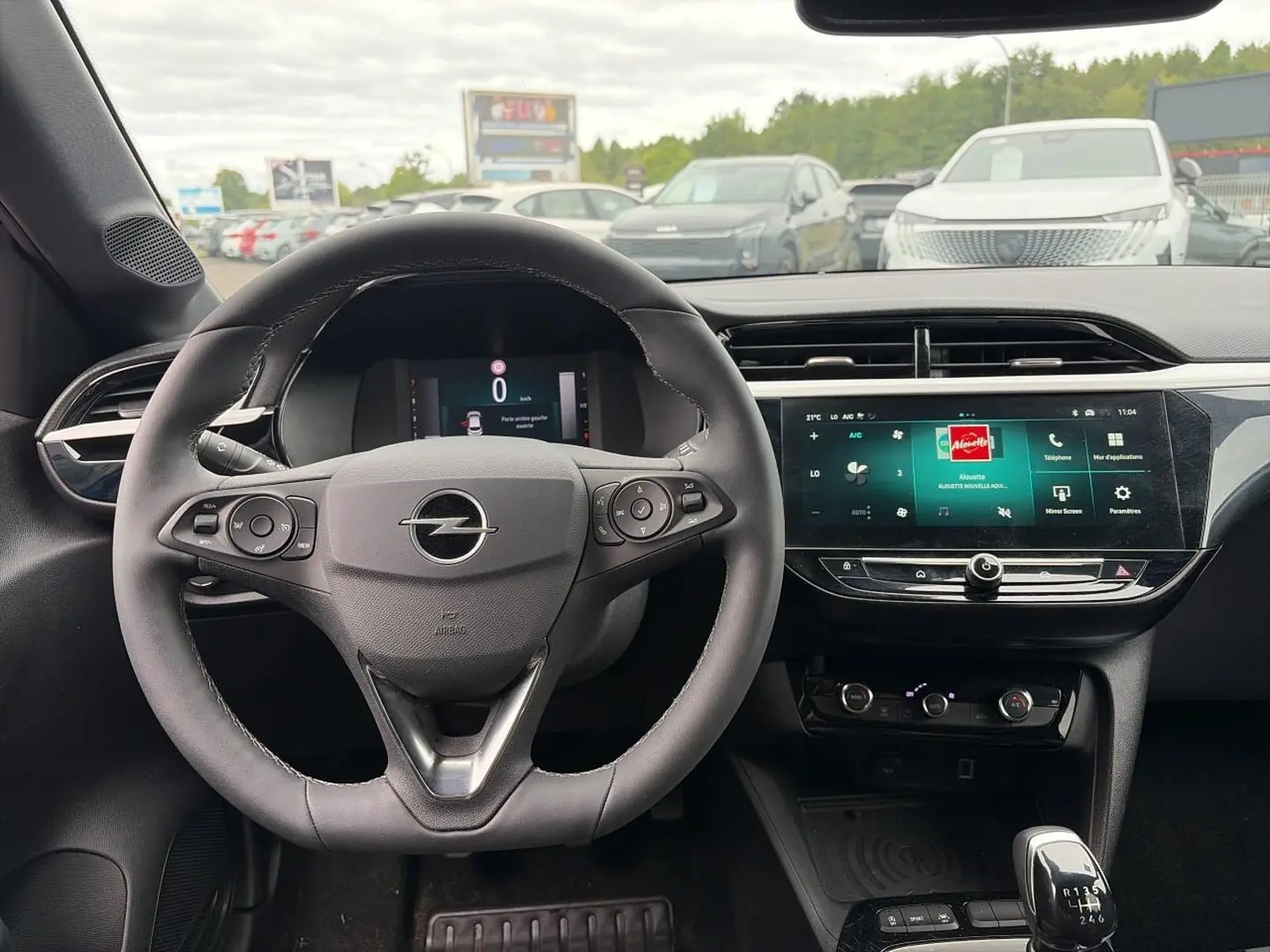 Vue intérieure centrée sur le volant sport Opel Corsa 2025 avec écran tactile et levier de vitesse manuel.