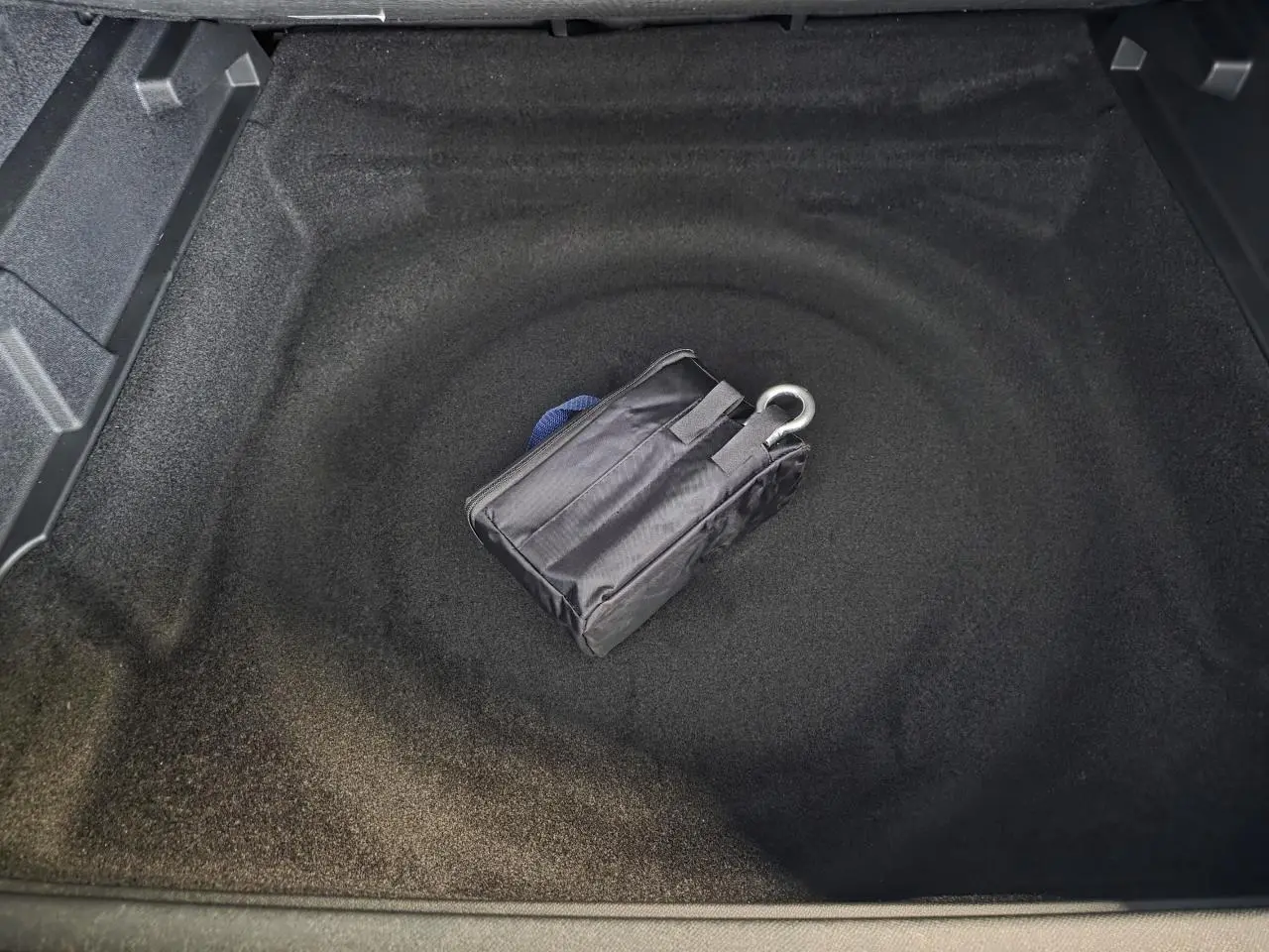 Coffre ouvert du Peugeot 3008 bleu, montrant un rangement sous plancher avec trousse de dépannage noire.