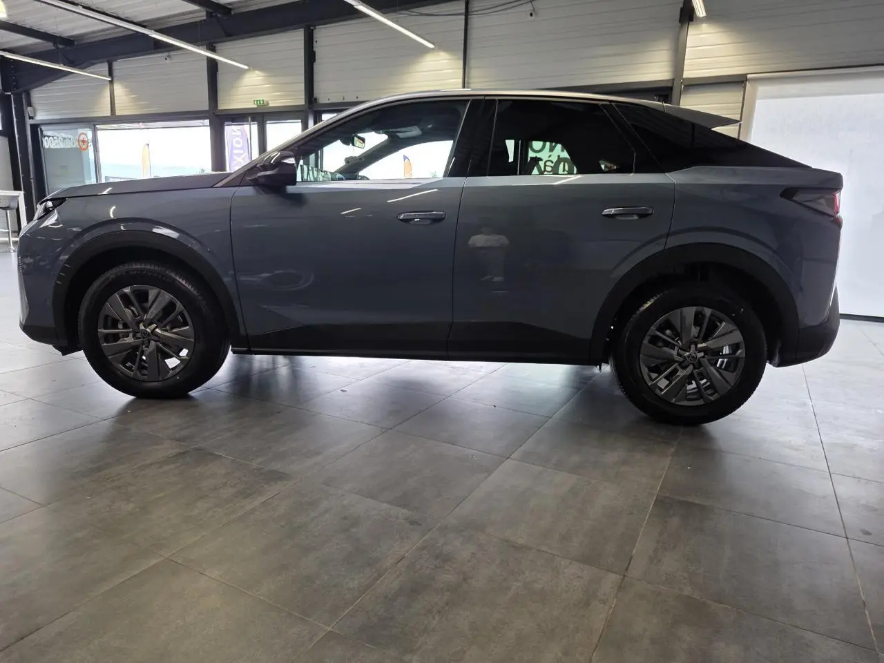 Vue de profil côté gauche du Peugeot 3008 hybride bleu, avec jantes alliage 18 pouces et toit noir contrasté.
