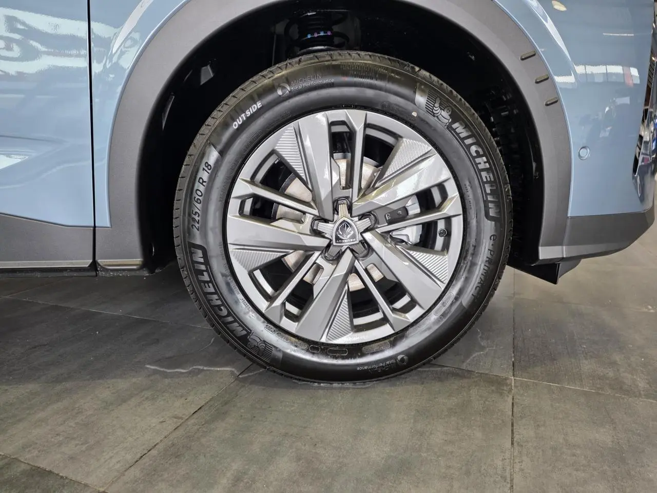 Gros plan sur la roue avant droite du Peugeot 3008 bleu, jante alliage 18 pouces au design moderne.