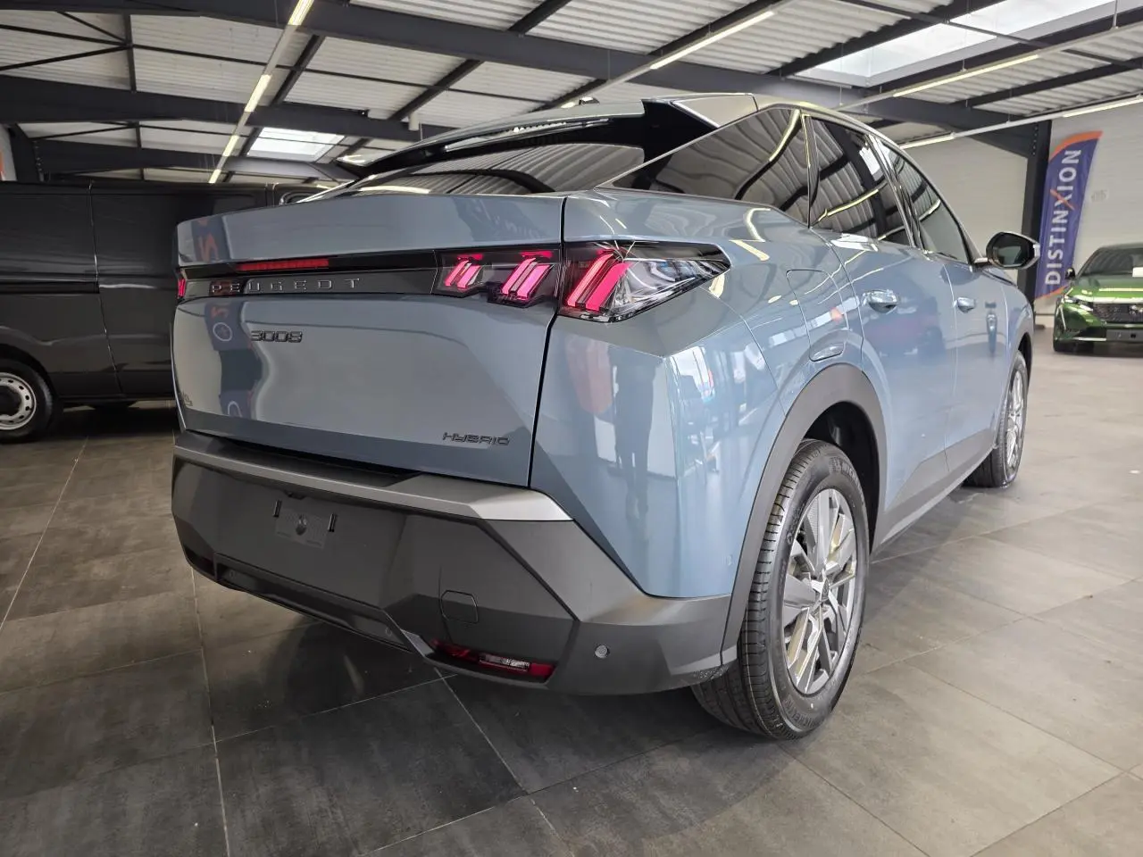 Vue 3/4 arrière droite du Peugeot 3008 hybride bleu avec feux arrière à LED en forme de griffes et bandeau noir laqué.