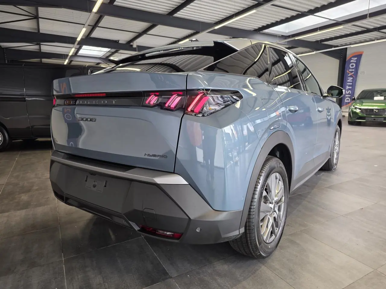 Vue 3/4 arrière droite d’un Peugeot 3008 hybride bleu avec feux arrière LED à 3 griffes et jantes alliage 18 pouces.