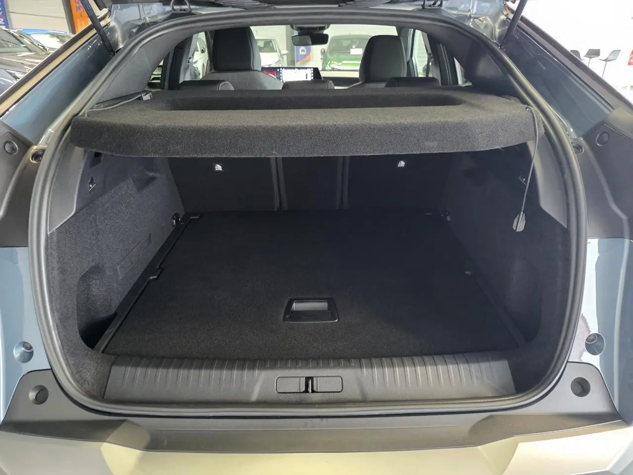 Coffre ouvert du Peugeot 3008 bleu, vue arrière montrant l’espace de chargement et la plage arrière relevée.
